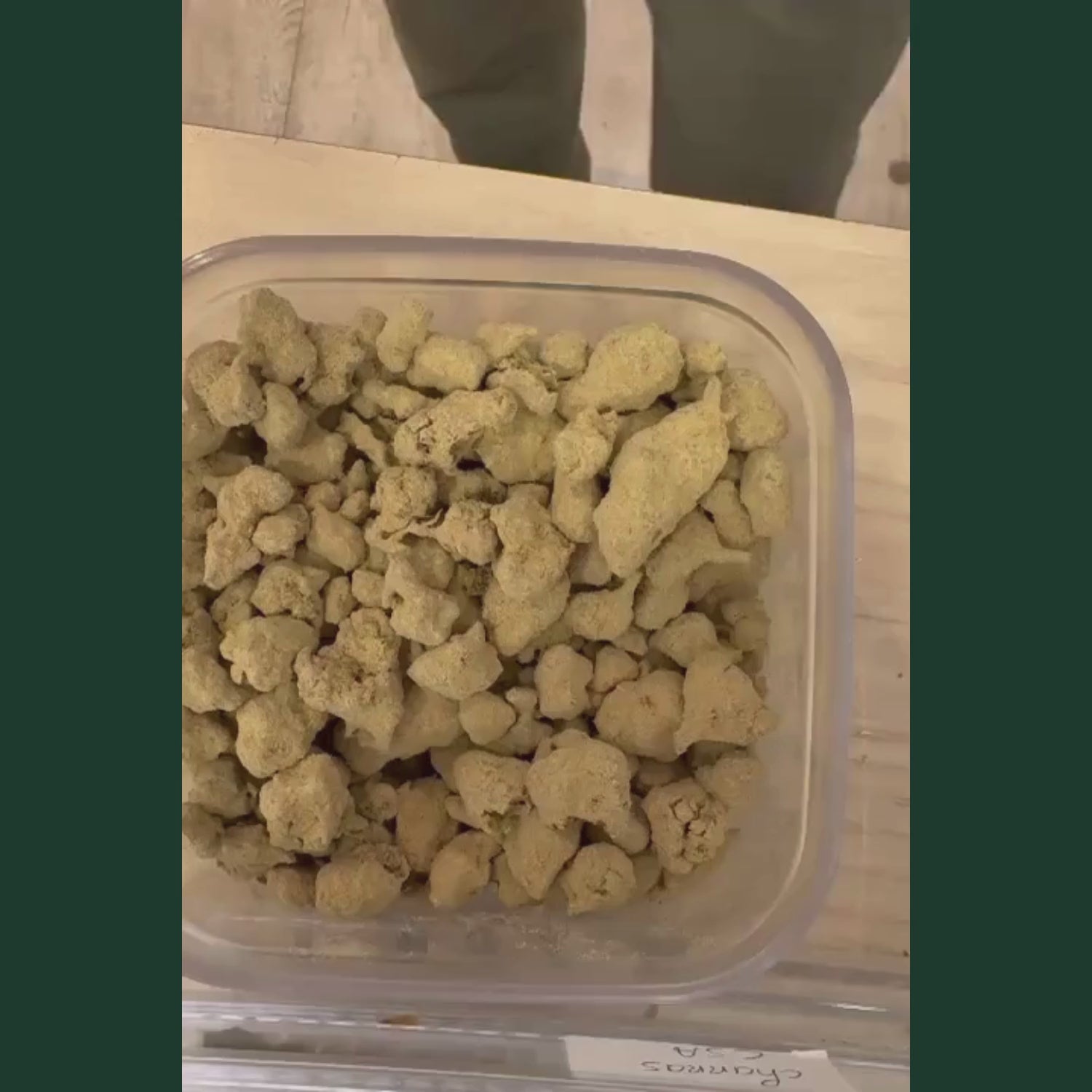 Video de presentation des Moonrock CBD+, nombreux morceaux de moonrock CBD en vrac de couleur beige creme et doree, texture granuleuse et poudreuse recouverte de trichomes cristallises, formes irregulières et volumineuses, presentes dans un contenant plastique transparent carré sur plan de travail clair, produit CBD legal France taux THC inferieur a 0,3%, moonrock CBD puissant disponible a l'achat sur cbdpaschre14.fr